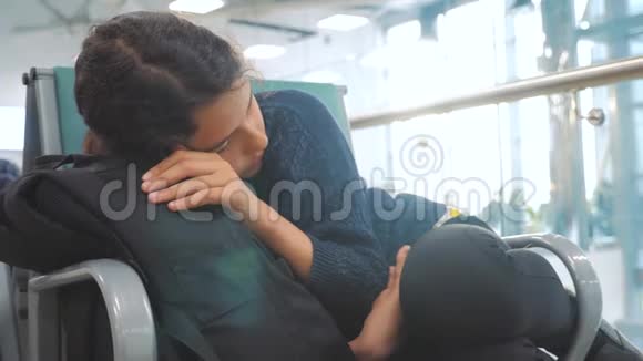 疲惫的少女少年旅行者在机场睡觉的生活方式等待着飞机起飞登机门和她所有的人一起坐长凳视频的预览图