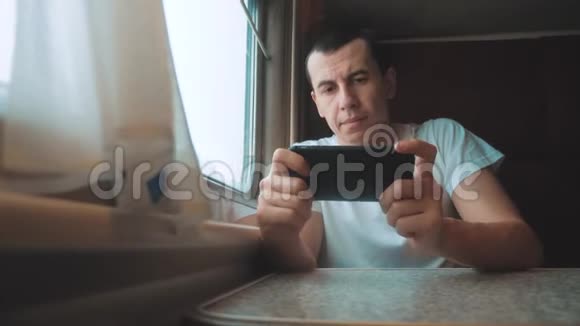 一个带着智能手机坐火车旅行的商人旅行者在火车上输入一条生活方式的网络信息视频的预览图