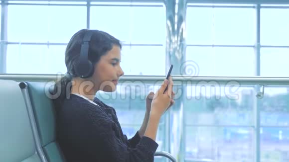 机场候机大厅生活方式房间供飞机飞行戴着耳机听音乐的年轻快乐少女视频的预览图
