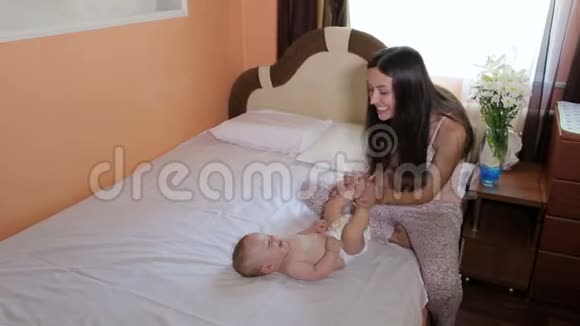 快乐的母亲和新生婴儿在床上玩耍视频的预览图