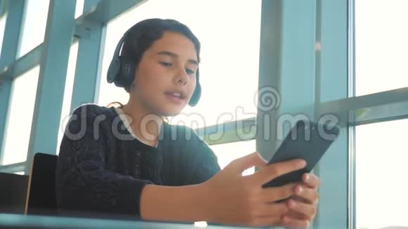 年轻快乐的少女戴耳机唱歌和听生活方式的音乐在智能手机上社交界的少女视频的预览图