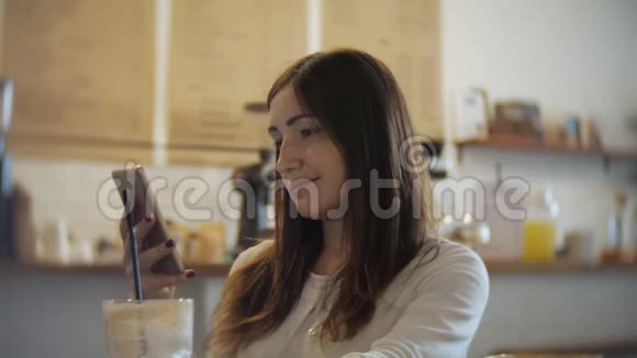 在咖啡馆喝咖啡和使用手机的年轻女子视频的预览图