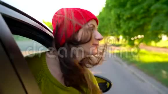 阳光明媚的一天幸福的年轻女子坐在副驾驶座上看着窗外视频的预览图