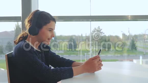 年轻快乐的少女戴着耳机听着智能手机上的音乐生活方式聊天交流视频的预览图