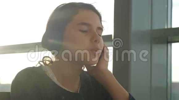 年轻快乐的十几岁女孩戴着耳机唱歌听着智能手机上的音乐社交网络中的少女视频的预览图