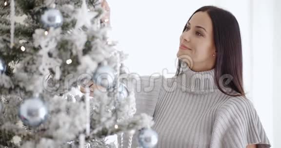 一个漂亮的年轻女人正在装饰圣诞树视频的预览图