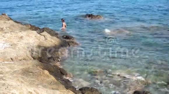 岩石海滩上美丽的年轻女士视频的预览图