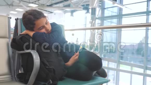 疲惫的少女少年旅行者睡在机场等待飞机起飞登机口的长椅上她的行李都在她身边视频的预览图