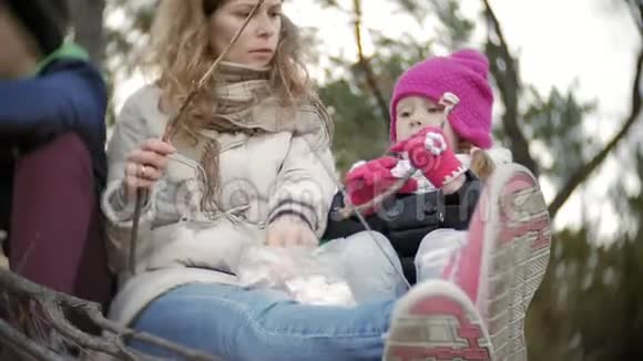 旅途中游客的幸福家庭妈妈和孩子们在帐篷附近的火上煎棉花糖视频的预览图