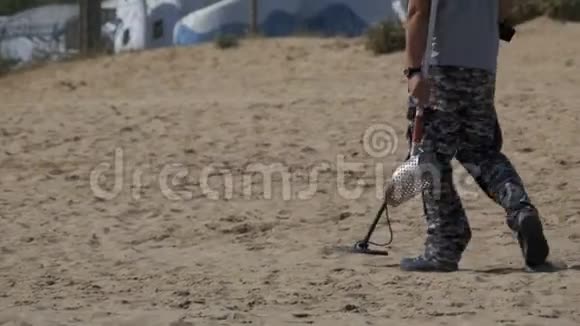 带金属探测器的人沿着海滨沙滩漫步视频的预览图