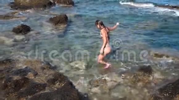 岩石海滩上美丽的年轻女士视频的预览图