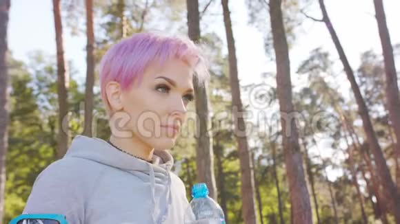 粉发在森林里慢跑的年轻女士视频的预览图
