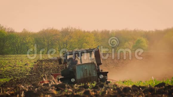 农用拖拉机播种栽培田拖拉机在日落时在田里工作视频的预览图