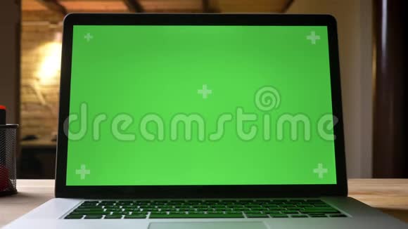 笔记本电脑的特写镜头上面有绿色屏幕广告放在办公室室内的桌子上视频的预览图