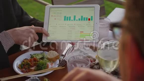 一个人用移动平板电脑在午餐时展示项目视频的预览图
