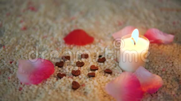 装饰玫瑰花瓣和蜡烛在沙子上燃烧的脚印情人节视频的预览图