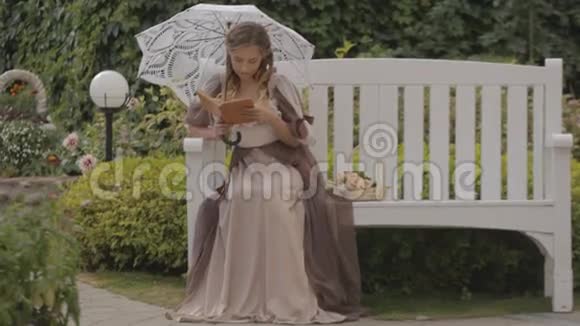 坐在长凳上的带着白色雨伞的女孩视频的预览图