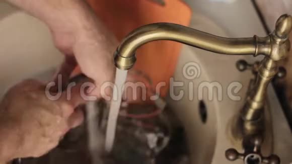 特写男士用手洗盘子用水喷射从泡沫和洗涤剂中冲洗盘子视频的预览图