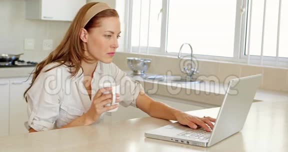 美丽的黑发女人喝咖啡用笔记本电脑视频的预览图