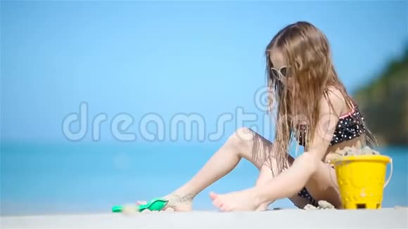 可爱的小女孩在海滩度假玩玩具视频的预览图
