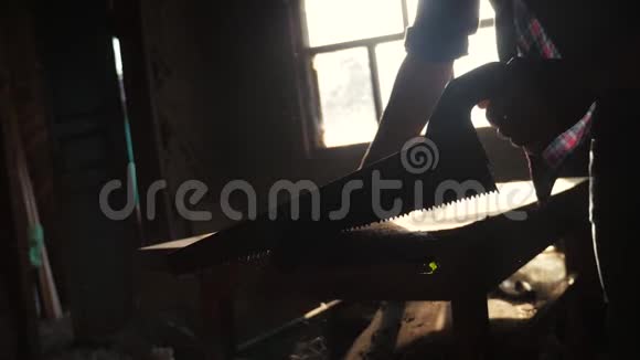 木工手工和工艺理念木匠在车间里锯一棵树从窗户的剪影里锯阳光视频的预览图