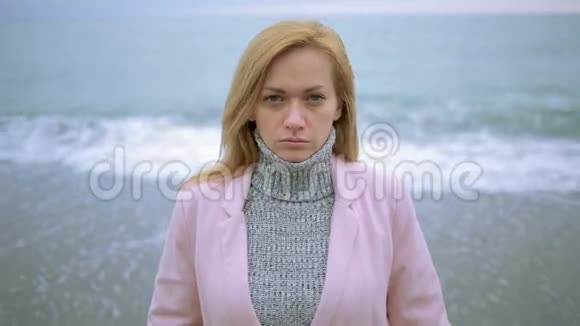 暴风雨时穿着粉红色外套的快乐女孩在海边大风视频的预览图