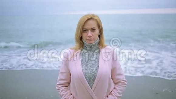 暴风雨时穿着粉红色外套的快乐女孩在海边大风视频的预览图
