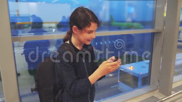 女儿带背包飞机飞行机场概念带着智能手机的少女望着窗外视频的预览图