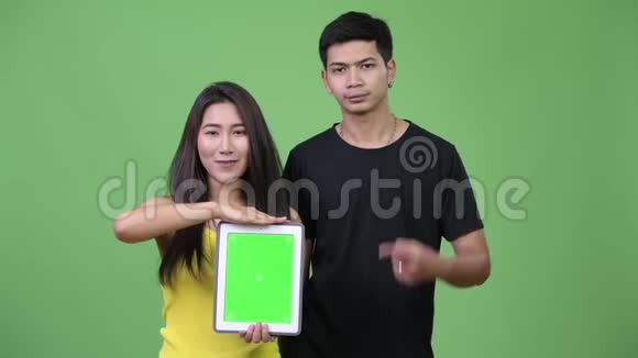 年轻的亚裔夫妇一起展示数码平板电脑视频的预览图