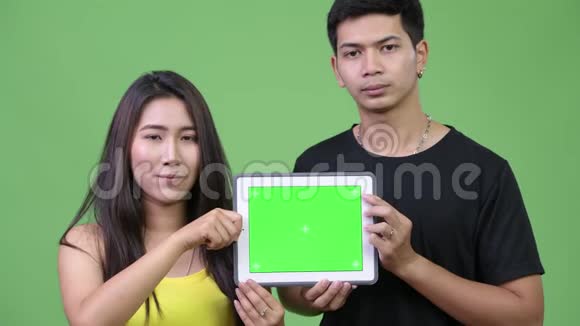年轻的亚裔夫妇一起展示数码平板电脑视频的预览图