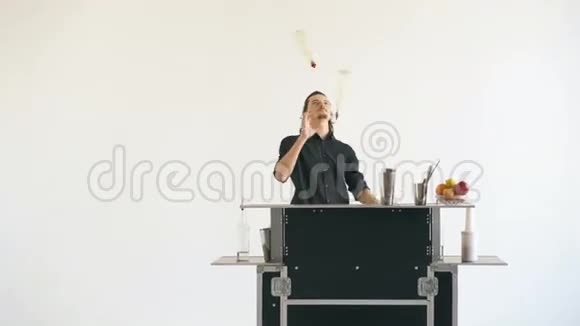 职业酒保男子在白色背景的移动酒吧桌上摆弄瓶子和摇晃鸡尾酒视频的预览图