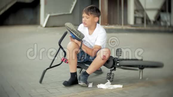 一个小男孩从自行车上摔下来后坐在公园里是一辆危险的自行车视频的预览图