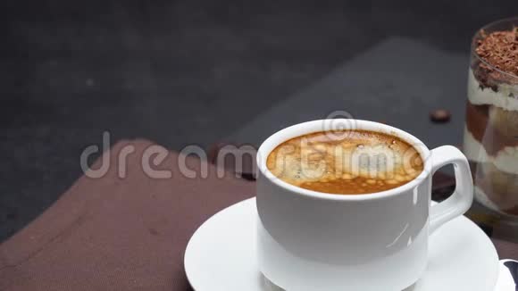 经典的提拉米苏甜点在一杯和一杯咖啡在黑暗的混凝土背景视频的预览图