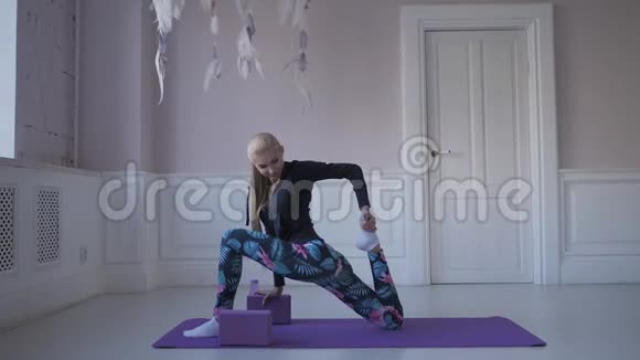 家庭健身年轻女子在训练前热身做伸展肌肉和关节的运动视频的预览图
