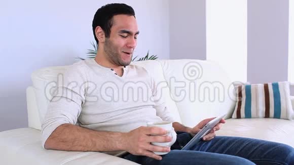 帅哥用平板电脑在沙发上放松视频的预览图