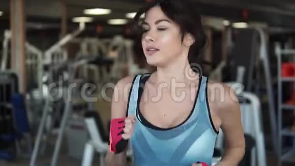 漂亮的年轻女孩在跑步机上跑步健身房的有氧运动视频的预览图