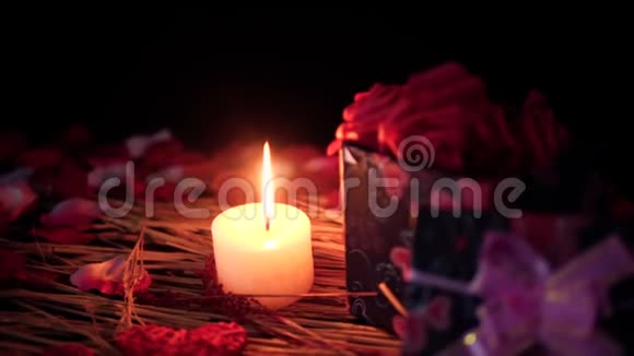 情人节快乐有礼物盒蜡烛燃烧和花瓣的镜头视频的预览图
