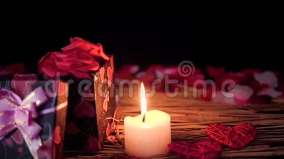 情人节快乐有礼物盒蜡烛燃烧和花瓣的镜头视频的预览图