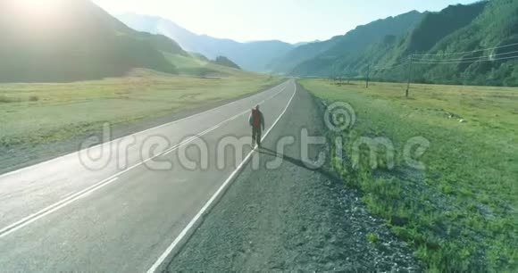 乘坐搭便车游客在沥青路上行走夏日的乡村山谷背包徒步旅行者视频的预览图