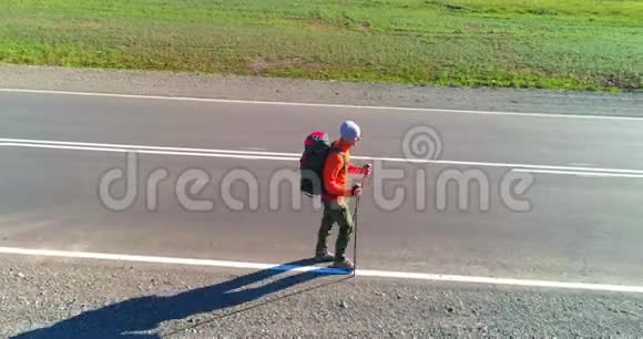 乘坐搭便车游客在沥青路上行走夏日的乡村山谷背包徒步旅行者视频的预览图