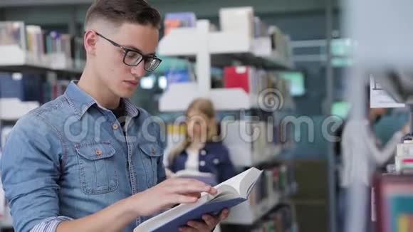 图书馆学生在书架附近看书视频的预览图