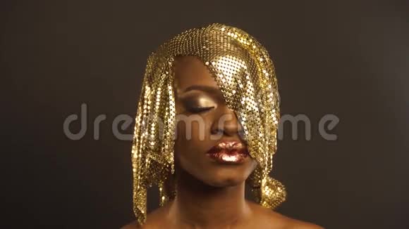 时尚肖像光泽非洲裔美国妇女与明亮的金色化妆青铜体漆黑色工作室背景视频的预览图