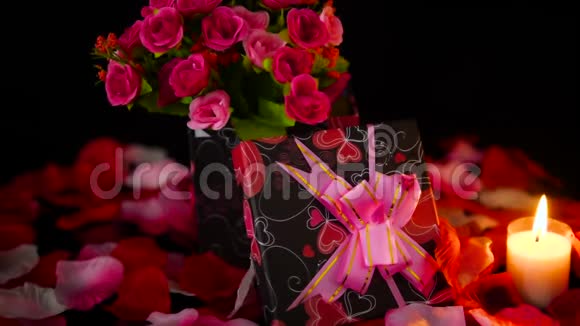 装饰情人节礼物盒蜡烛燃烧和玫瑰花瓣镜头视频的预览图