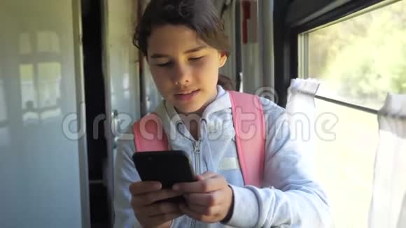 带背包的少女旅行者站在装有智能手机的火车车窗旁旅行交通视频的预览图