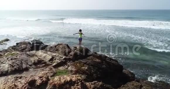 女人在海边的悬崖边张开双臂视频的预览图