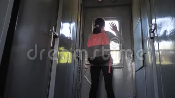 带背包的少女旅行者站在火车的窗户边手里拿着一部智能手机旅行交通视频的预览图