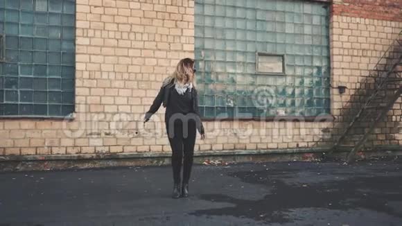 女人在街上的砖工业建筑的墙边跳舞视频的预览图