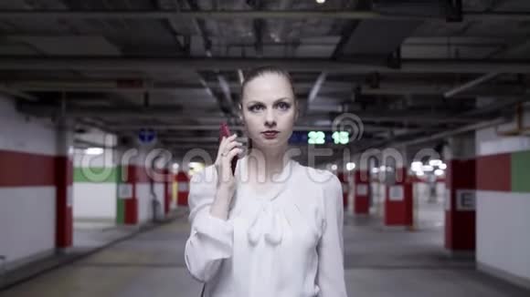 穿着白色衬衫和黑色裙子的漂亮年轻女子在地下停车场视频的预览图