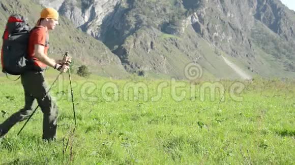 徒步旅行者带着背包在绿色的山地草地上行走夏季运动和娱乐理念视频的预览图