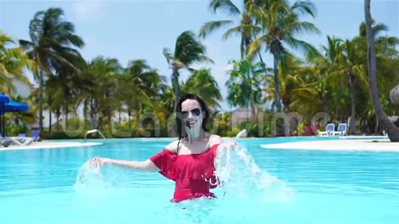 美丽的年轻女子在游泳池里放松豪华酒店室外游泳池的快乐女孩视频的预览图